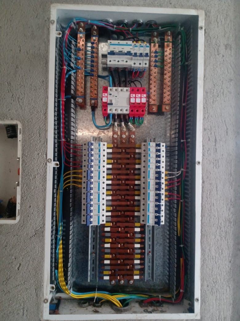 Quadro de distribuição maior com DR e protetores contra surto vermelhos na entrada, barramentos de cobre nas laterais e duas réguas de disjuntores, cabos organizados em canaletas, montado pela J&C Elétrica.